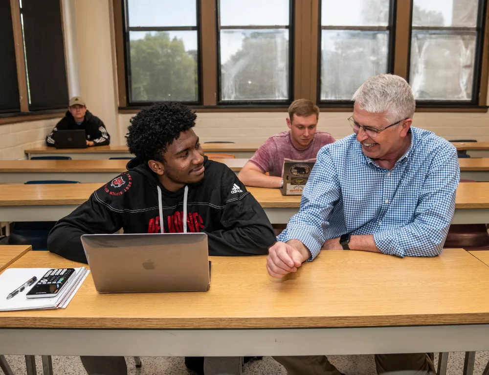 Accounting student and professor sitting at table with A-State hoodie and laptop
