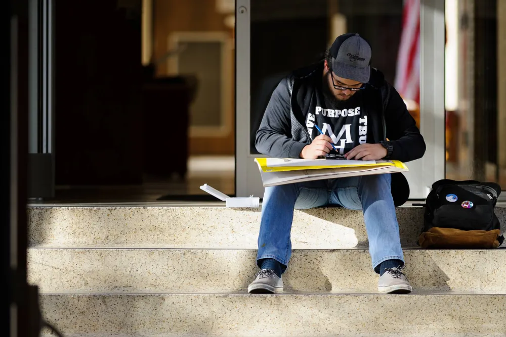 A student drawing on a staircase.