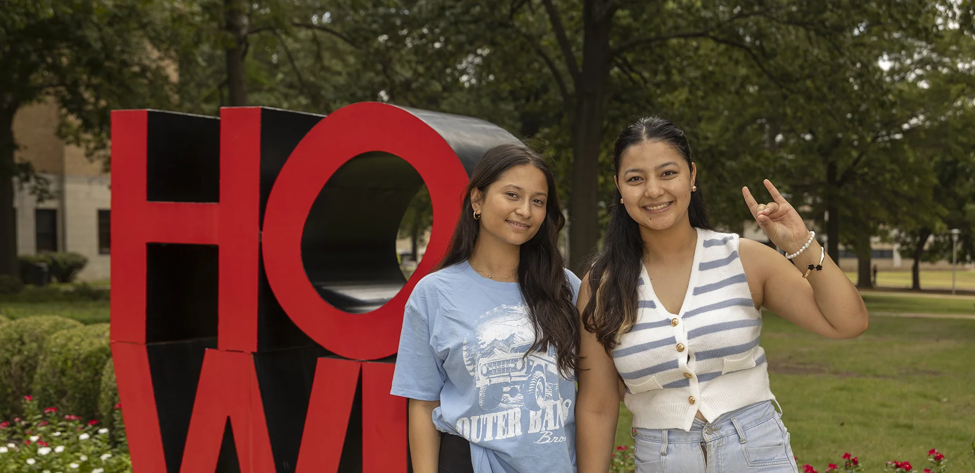 Two students doing Wolves Up in front of the HOWL statue.