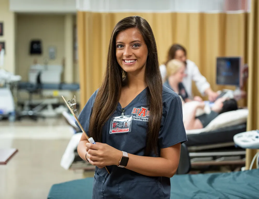 Student posing at NEA hospital for a picture while doing a radiology lab with ultrasounds.