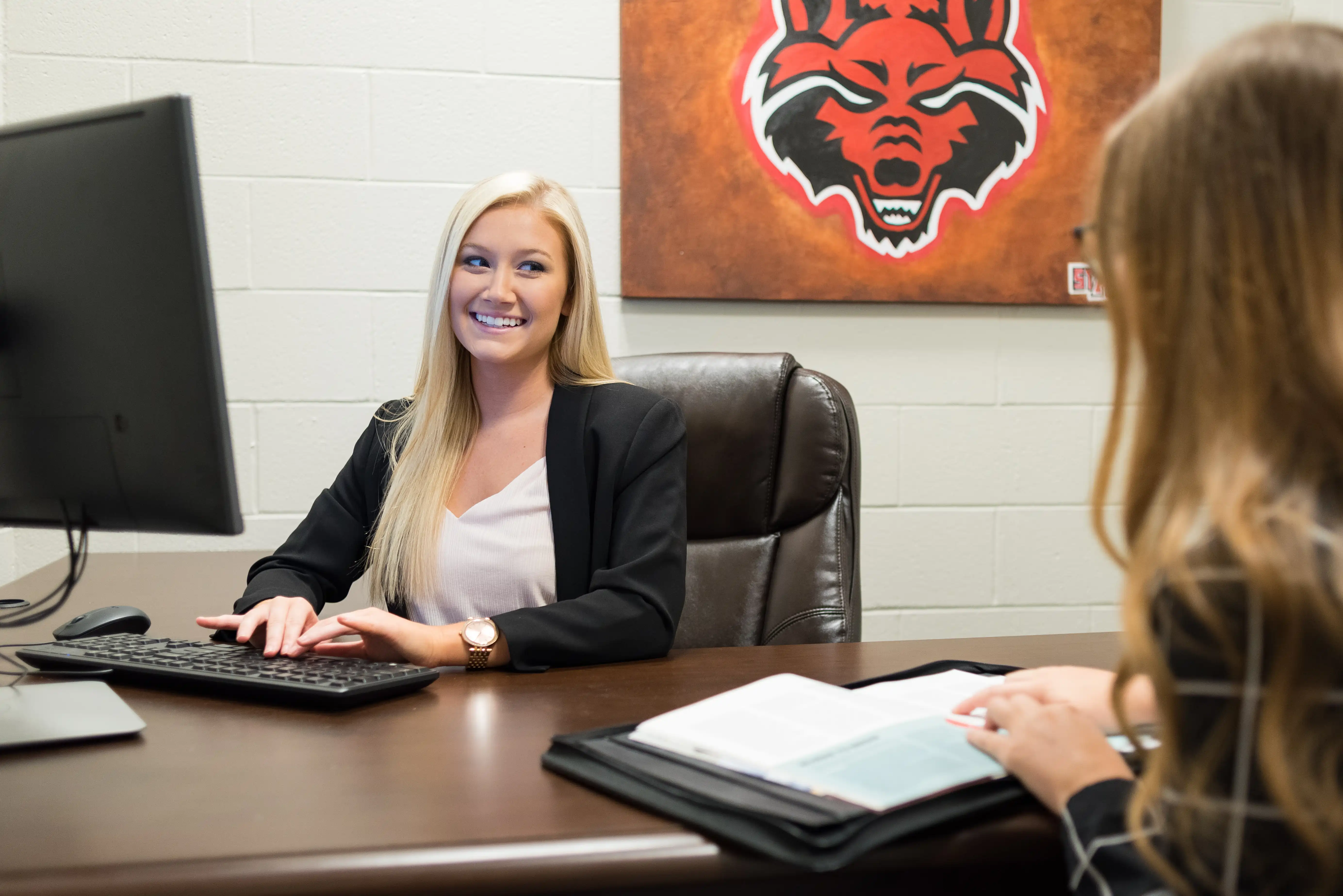 A-State student sitting at a desk doing mock interviews in a business class.