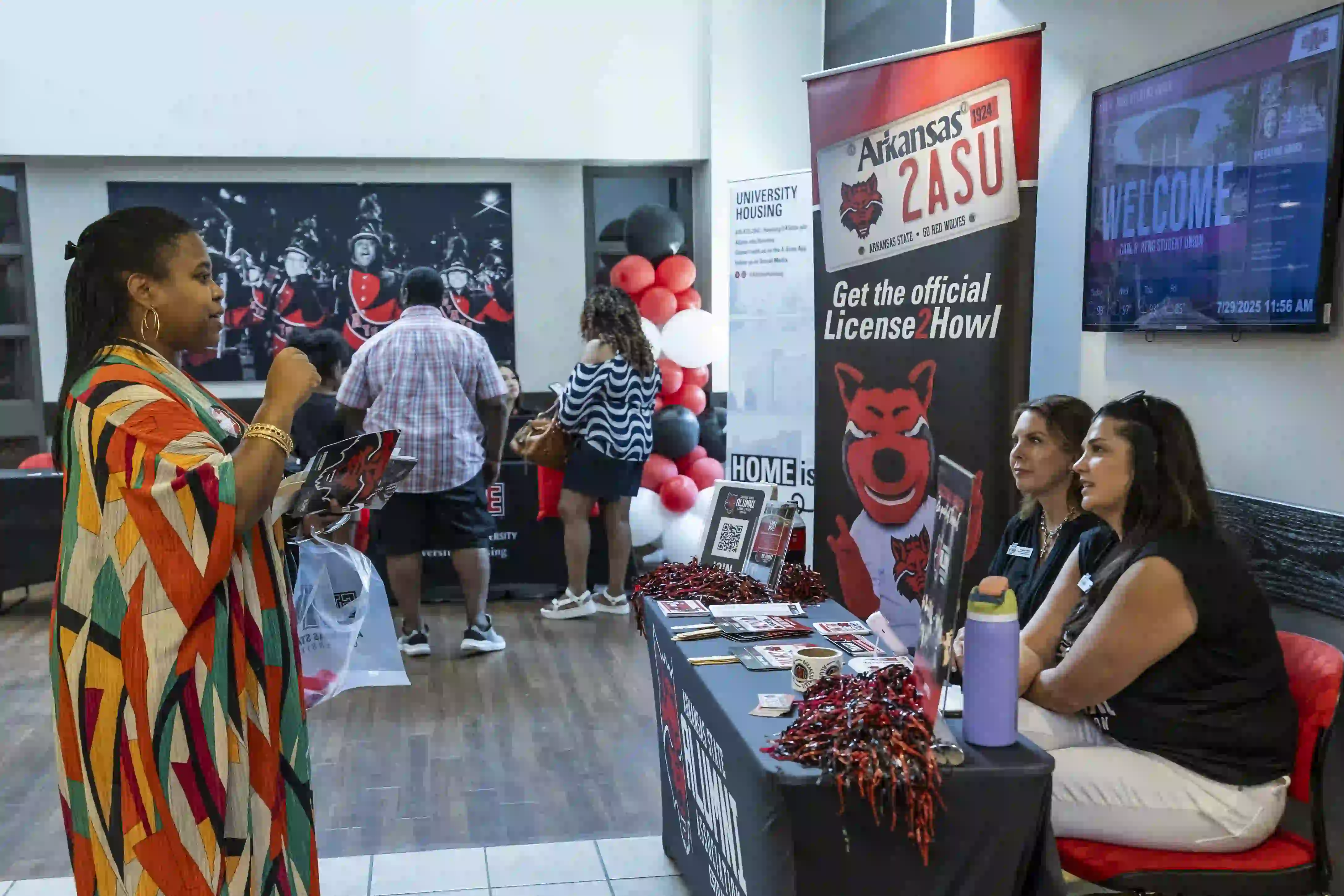 Staff sitting at table talking to parent during New Student Orientation.