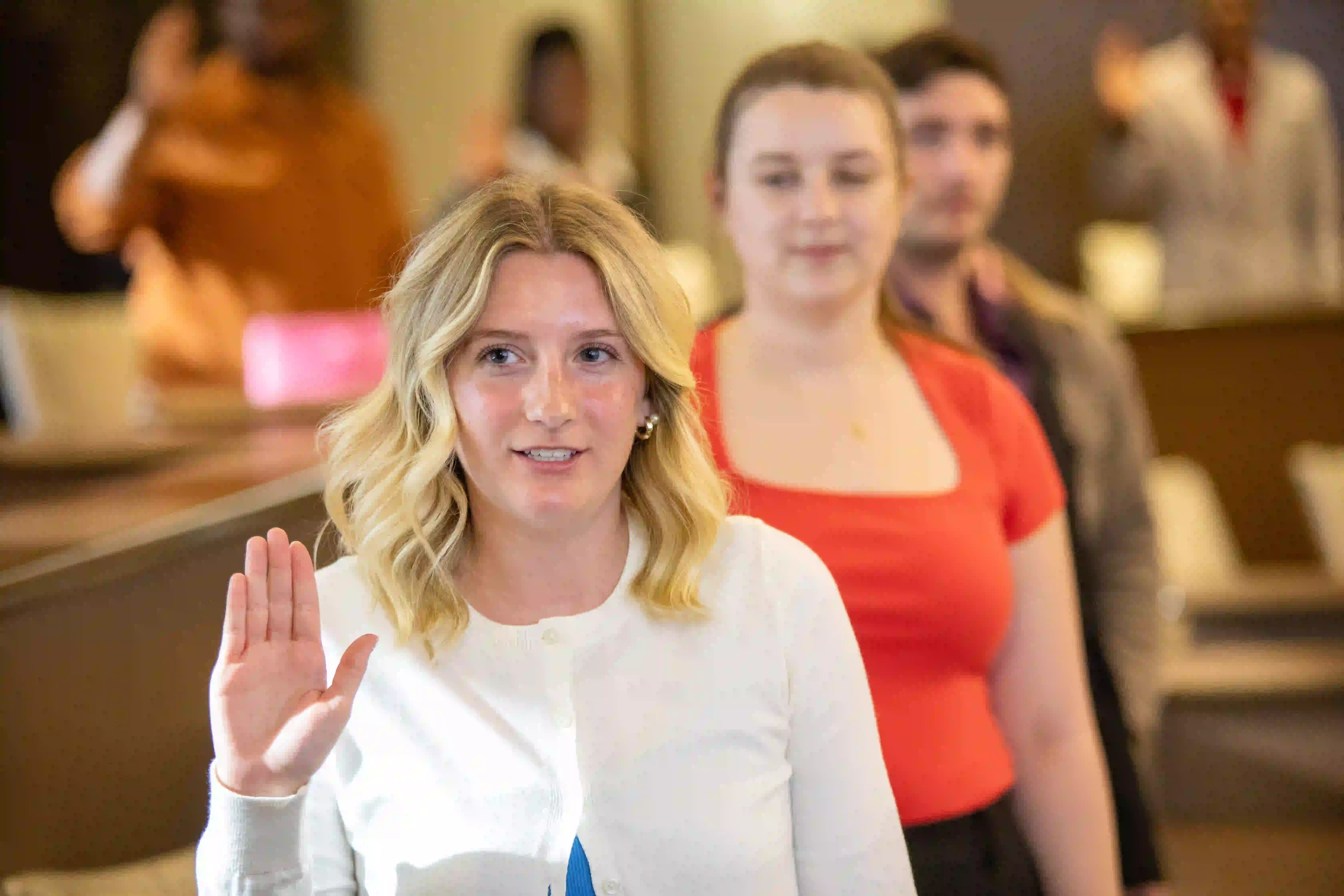 Student holding up hand as they are sworn in during a Student Government Association meeting.