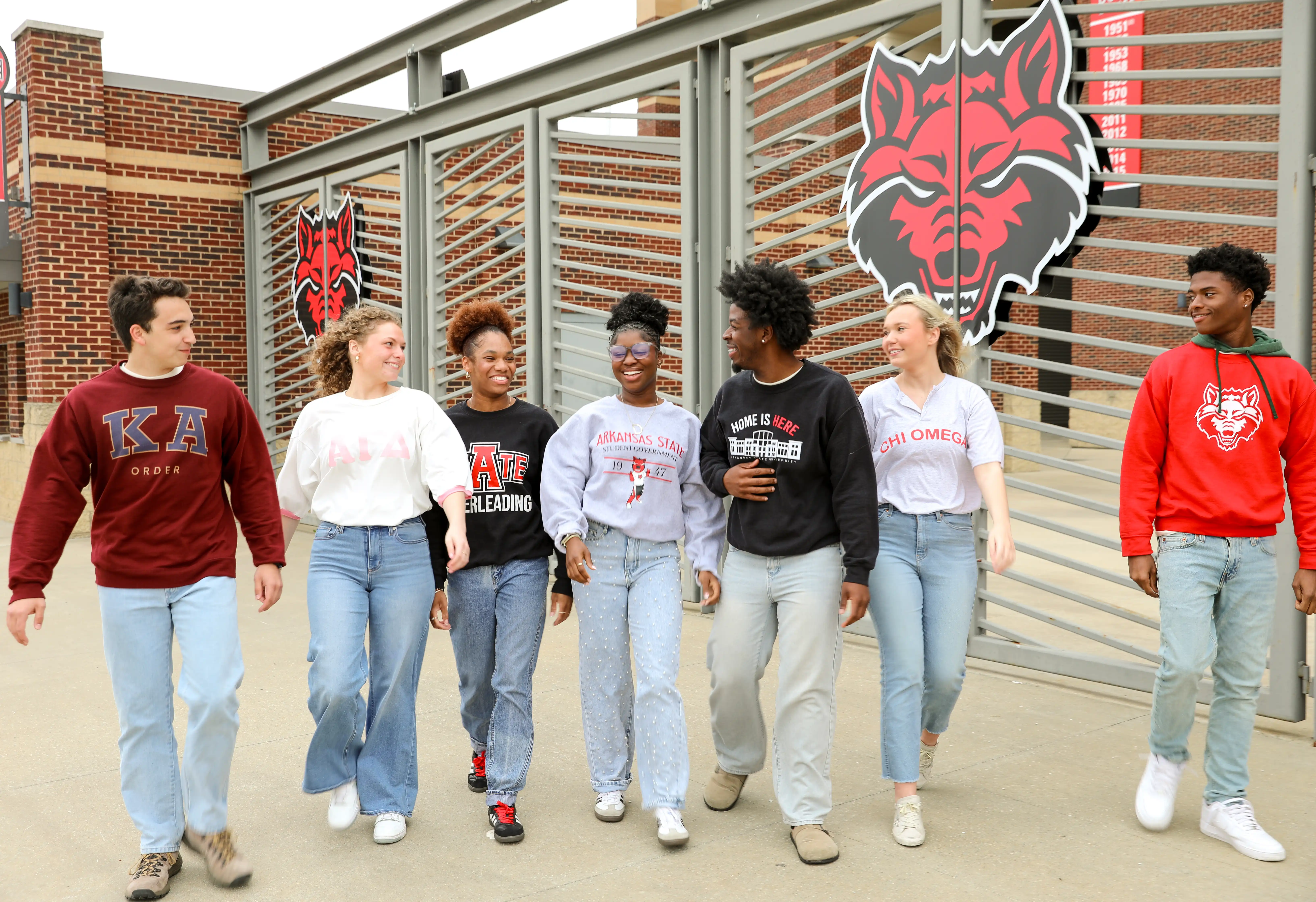 Student Government Association students walk together at the gates to Centennial Bank Stadium.