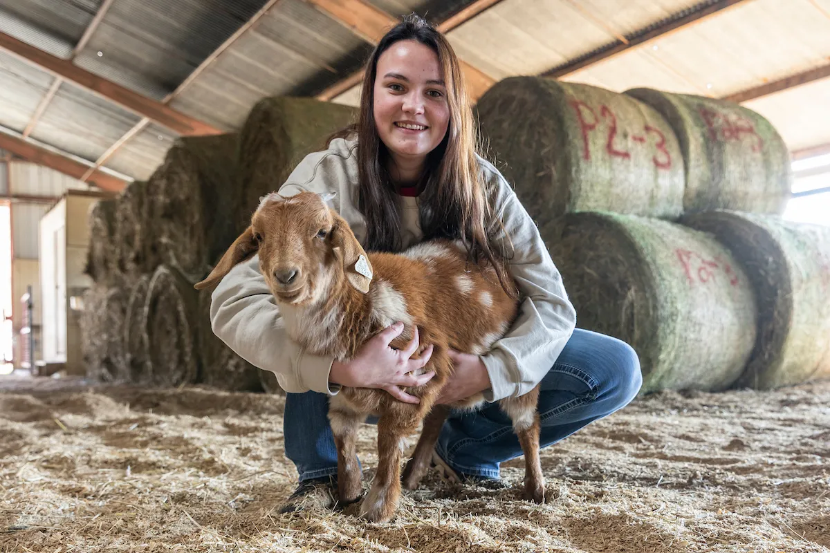 An A-State student holds a goat in the A-State Equine Center