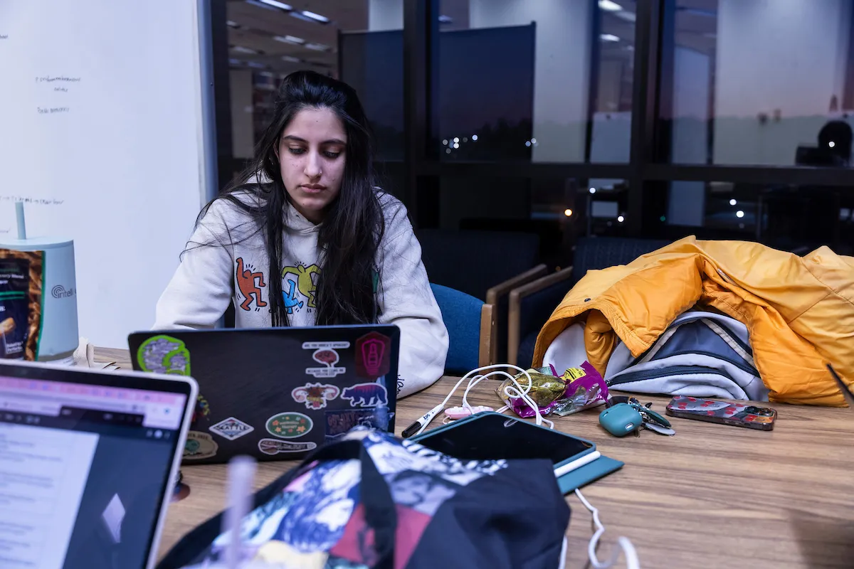 A student uses a laptop at the table in the common area of the library.