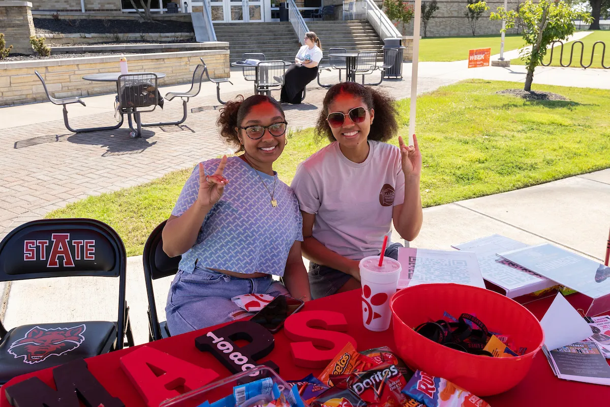 Two students give their Wolves Up at a table.