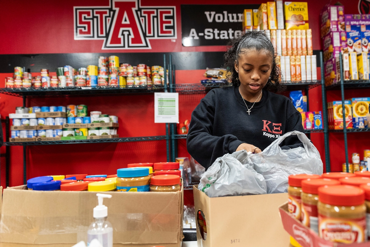 Student packing box on table at food pantry.