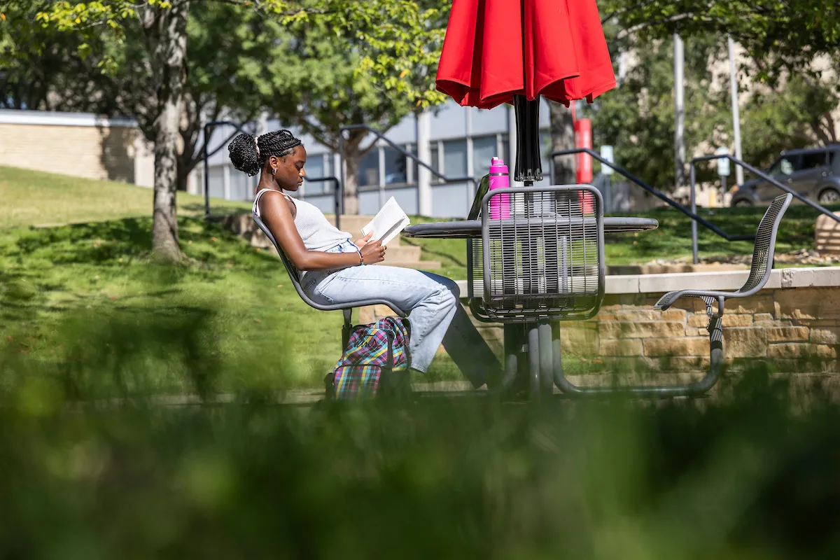 Student reading a book under a red umbrella