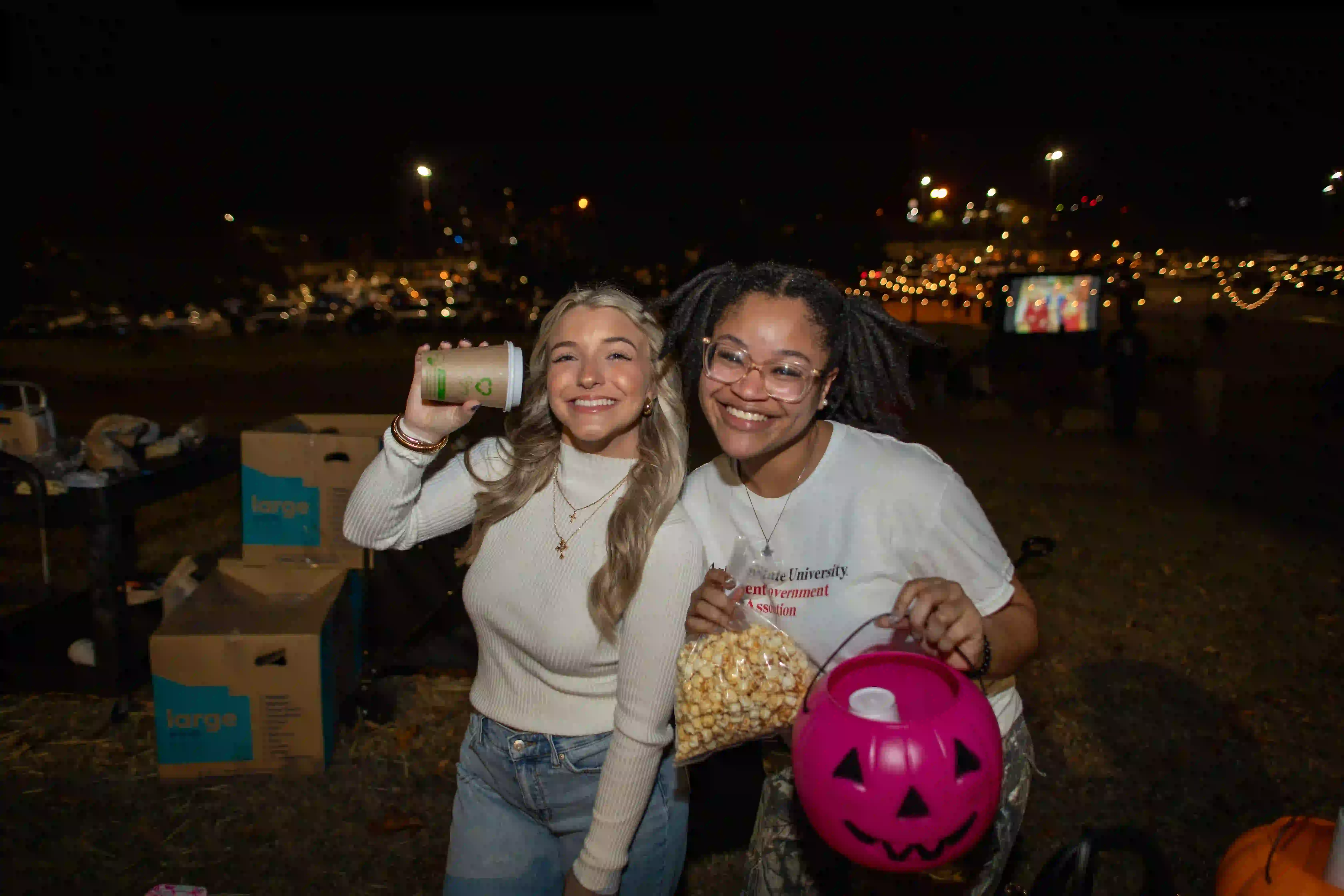 Students serving popcorn at Halloween event.