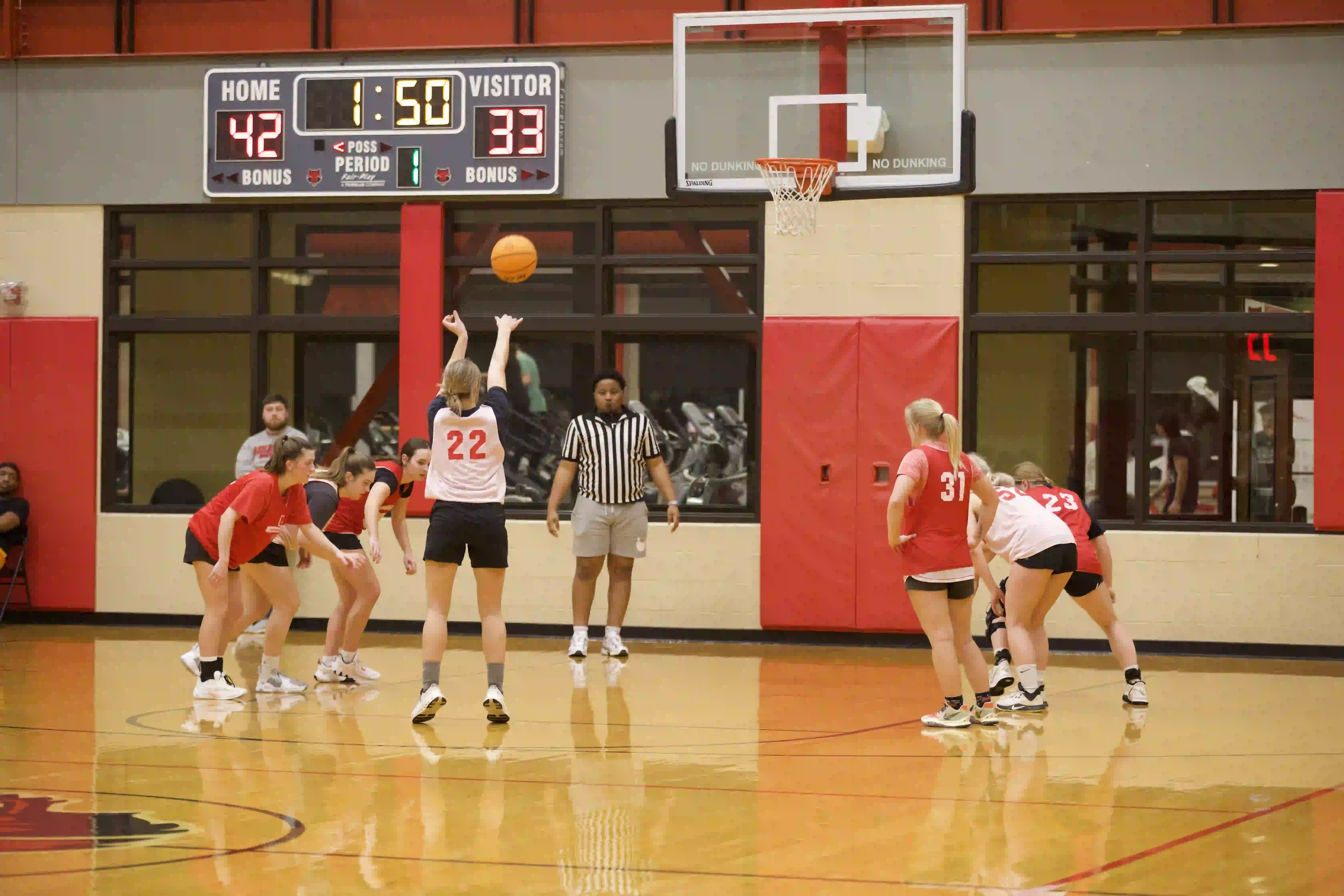 Students playing intramural basketball in gymnasium at Red WOLF Center with referee.