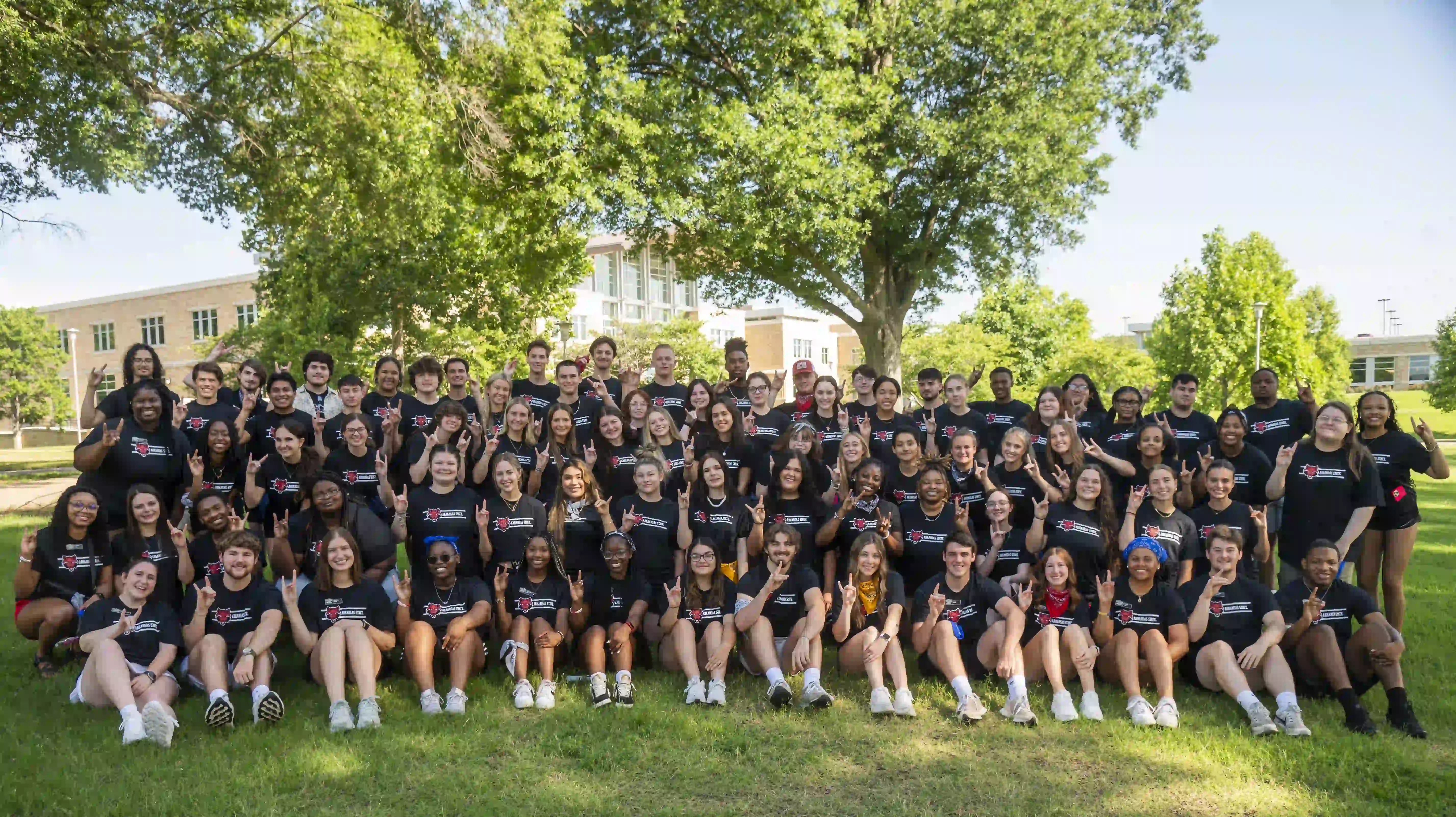 Group of students posing in matching t-shirts in front of Student Union.