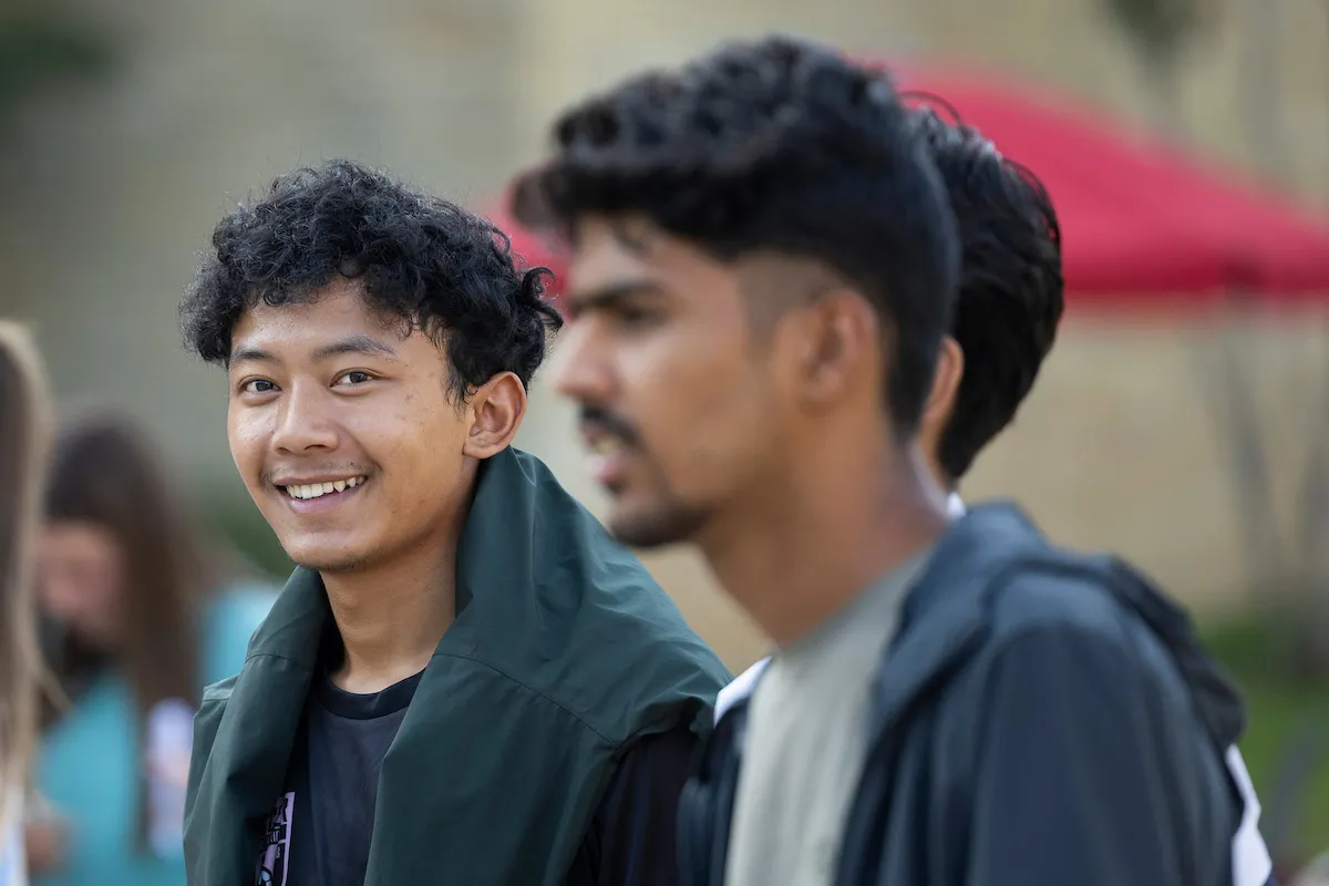 An international student smiles at the camera during a student event in front of the Reng Student Union