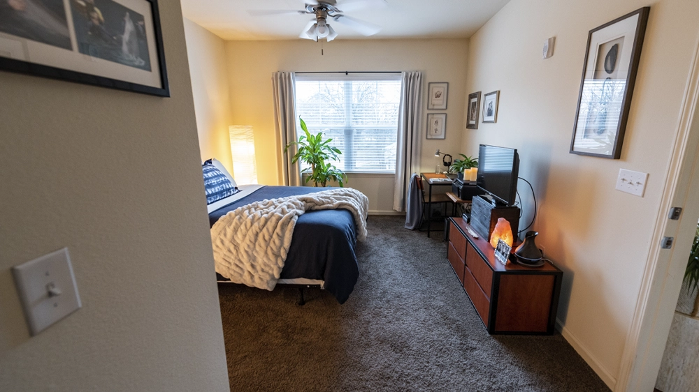 Hallway view leading into a bedroom with large window and cozy decor.