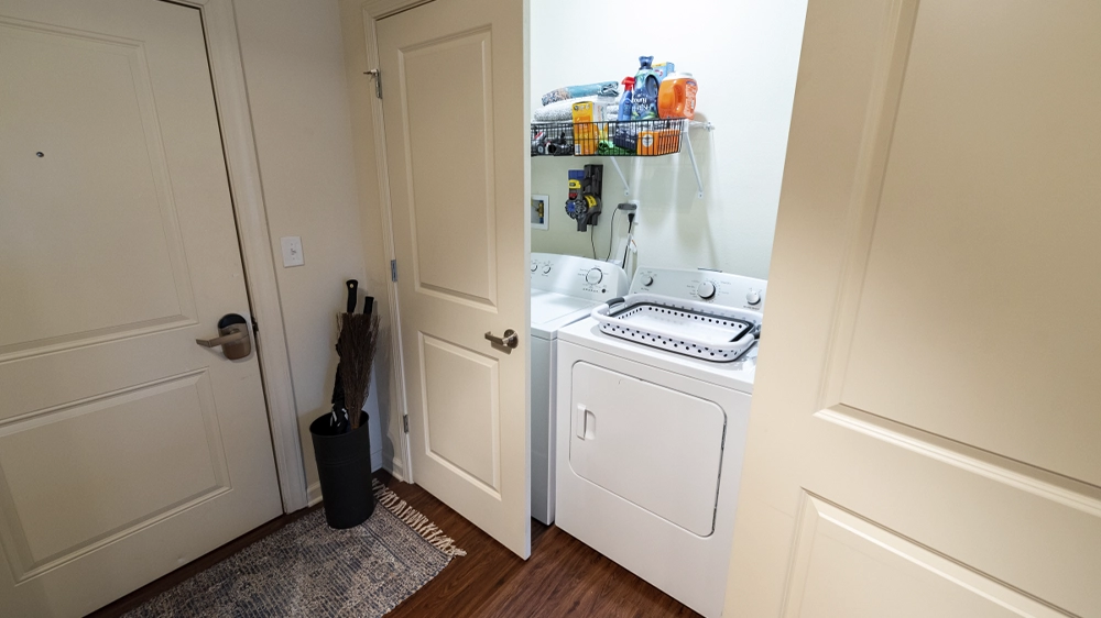 Laundry closet with washer and dryer and overhead shelving for supplies.