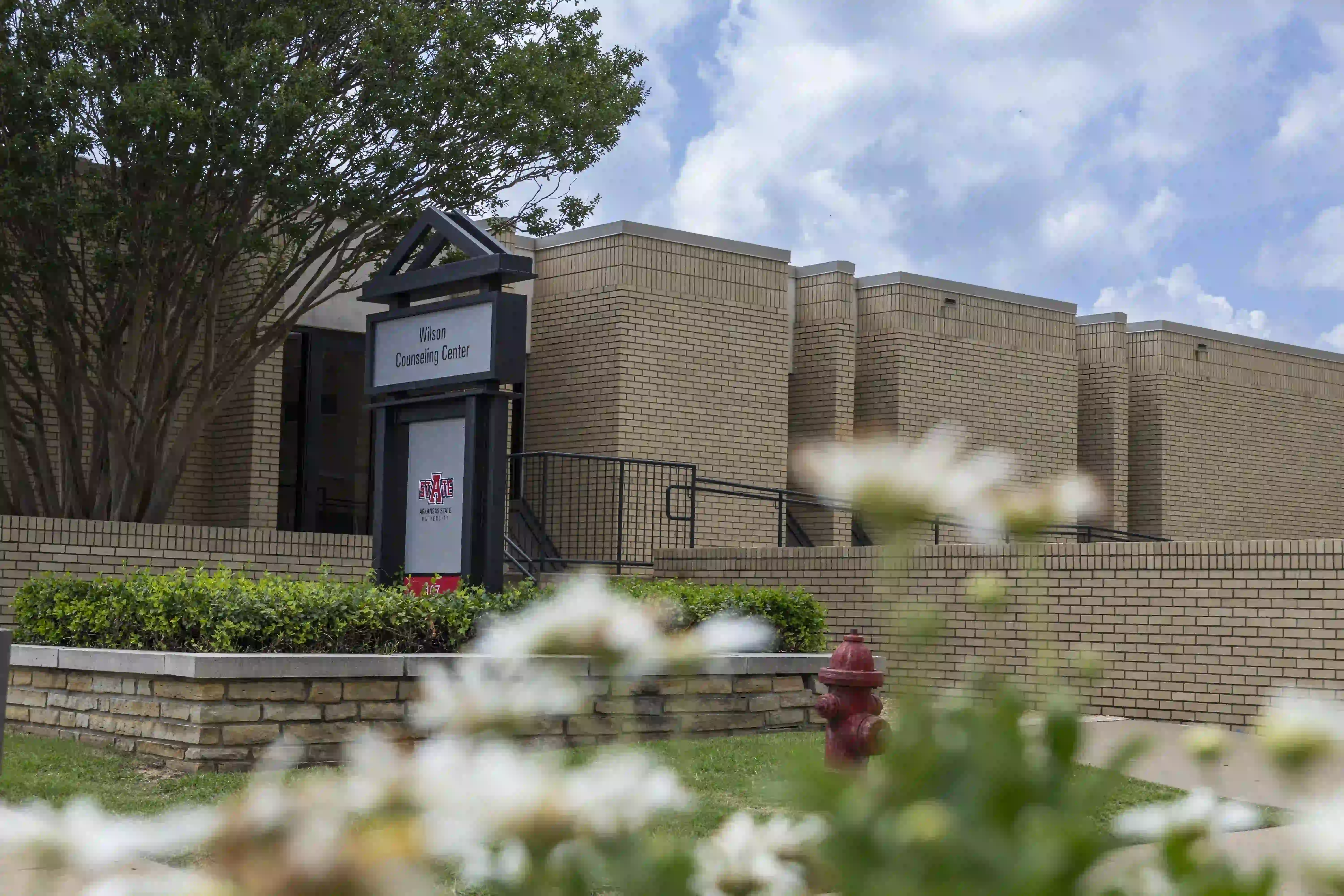 Wilson Counseling Center sign outside building with flowers and fire hydrant.