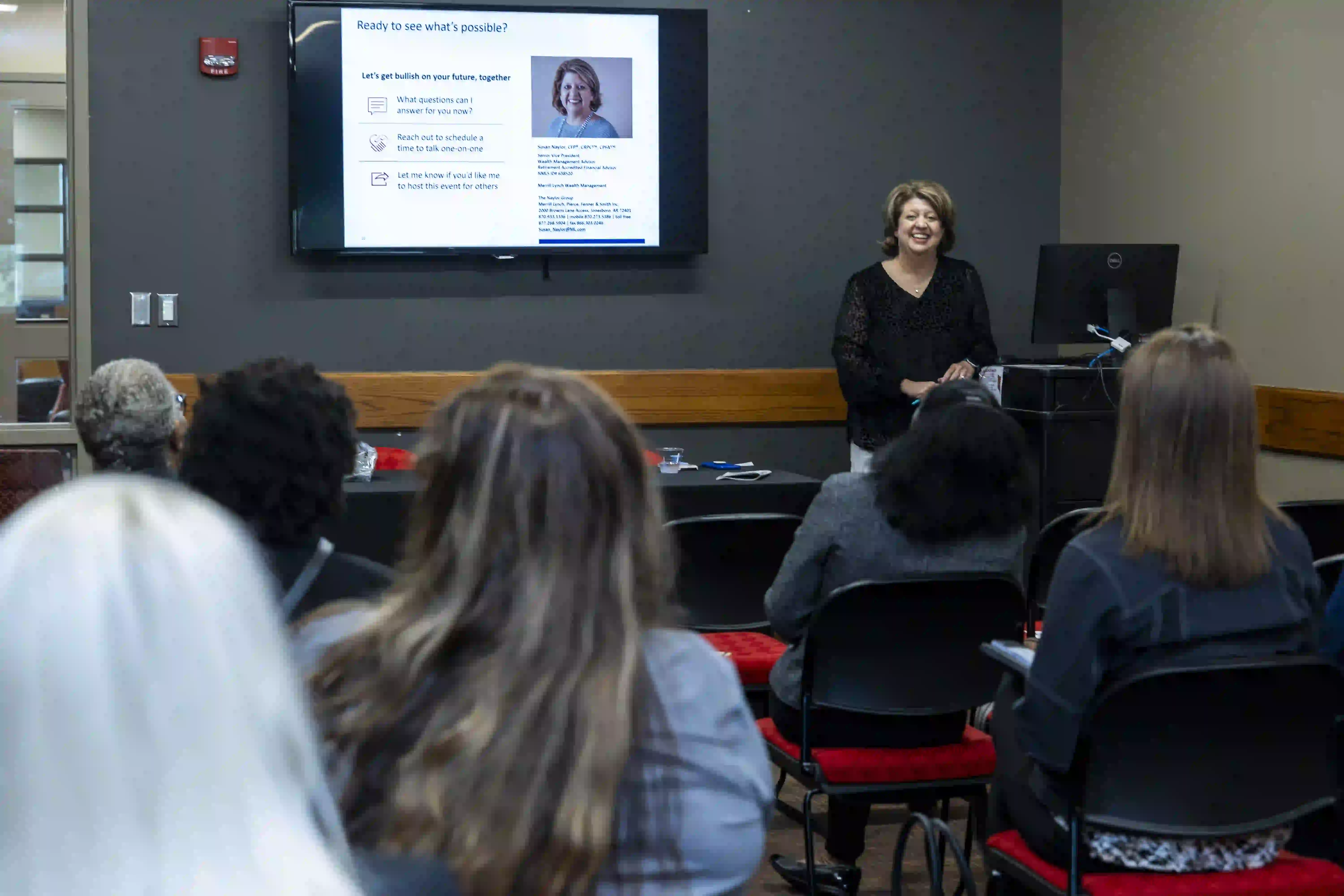 Speaker at front of meeting room giving a presentation.